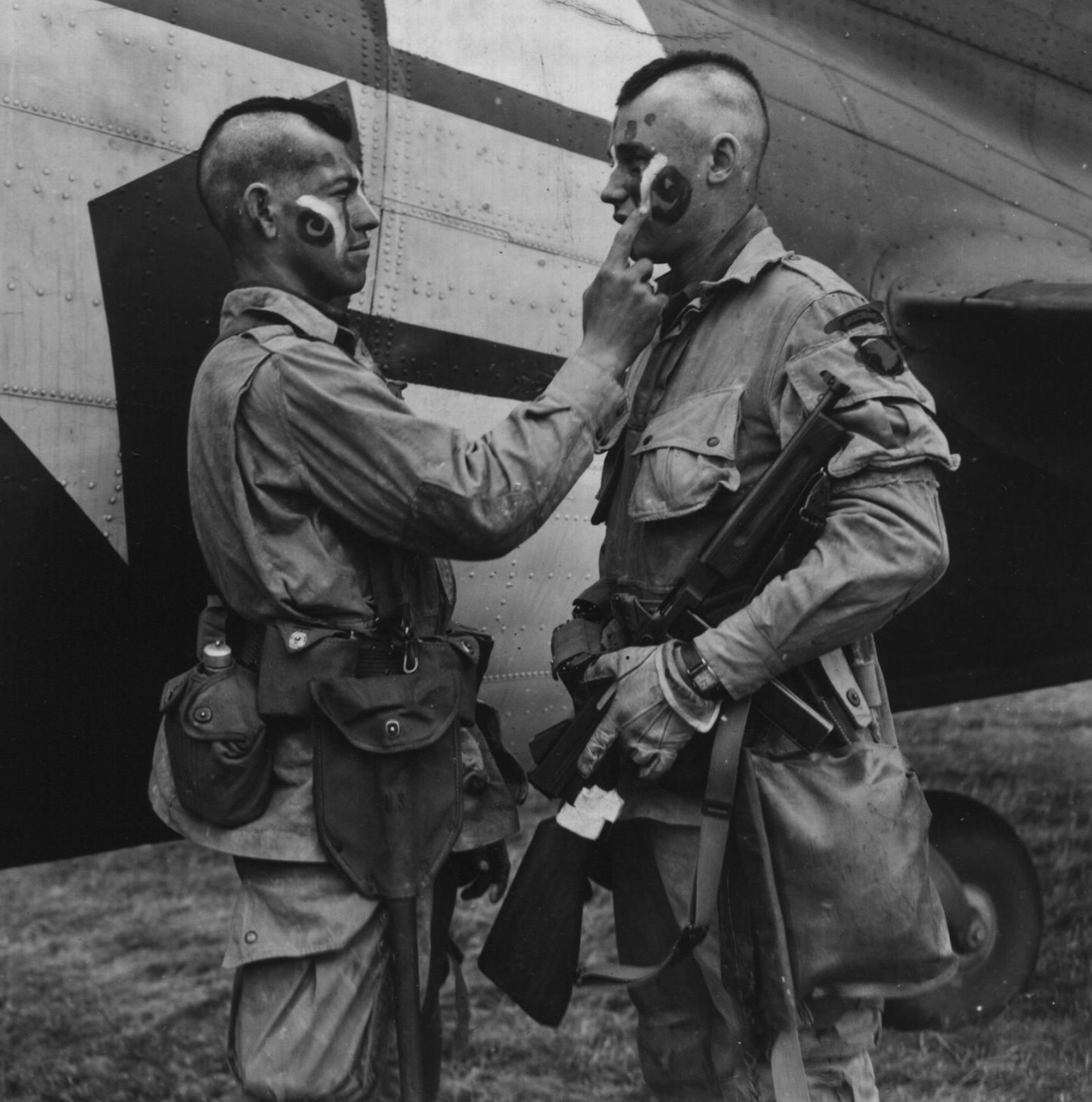Paratrooper Private Ware applies last second make-up to Private Plaudo in England, June 1944.